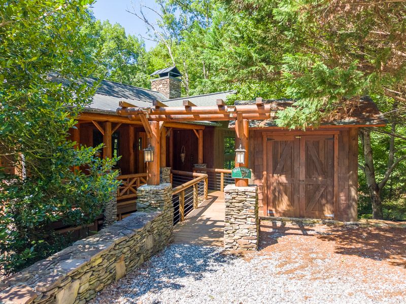 Log pergola and stone walls at the front entry in daylight