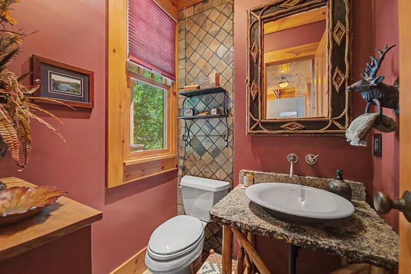 Powder room with a granite-topped vessel sink and tiled accent wall