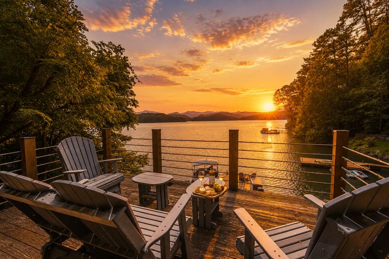 Adirondack chairs on the dock facing a sunset over the lake