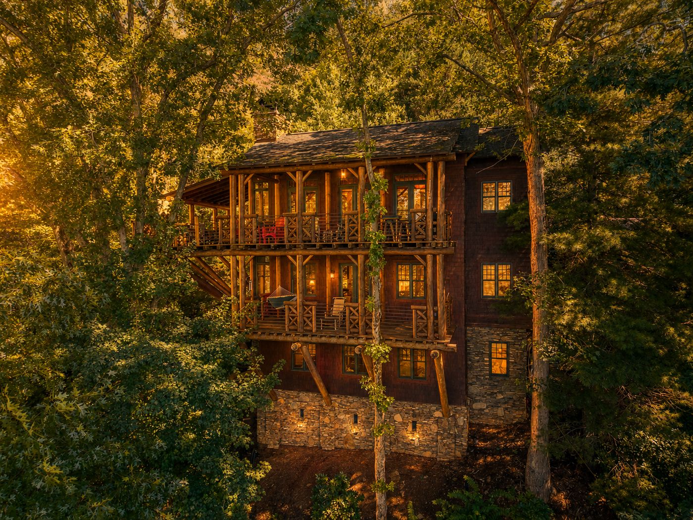 The Treehouse at golden hour, its three balconied stories lit from within among the trees above Lake Santeetlah