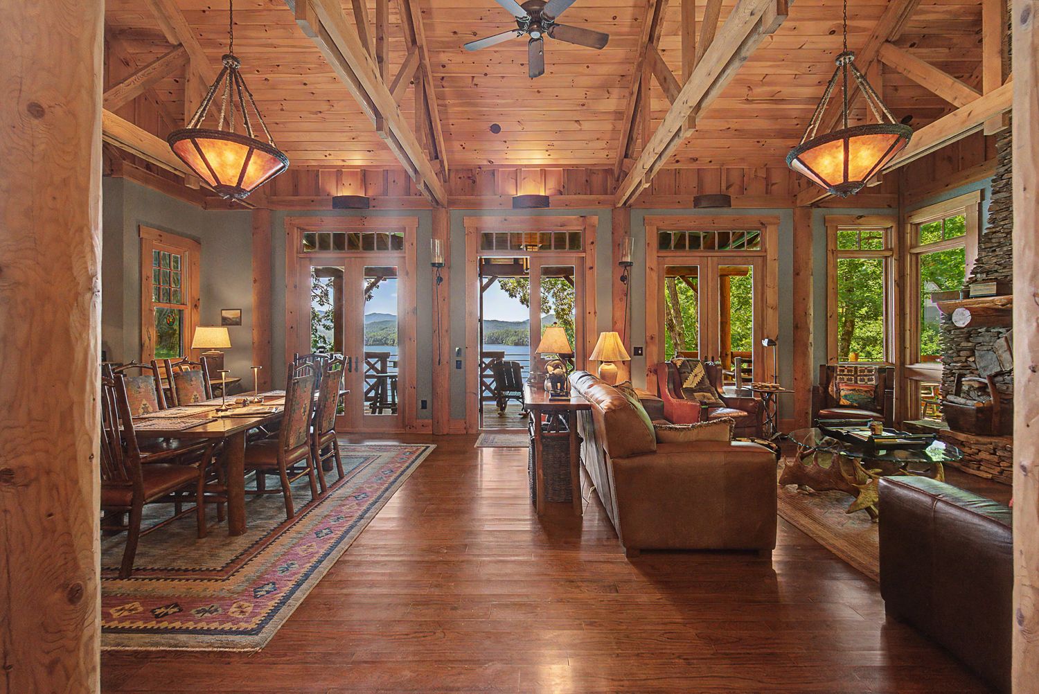Dining table under the trusses with French doors opening to the deck and Lake Santeetlah beyond