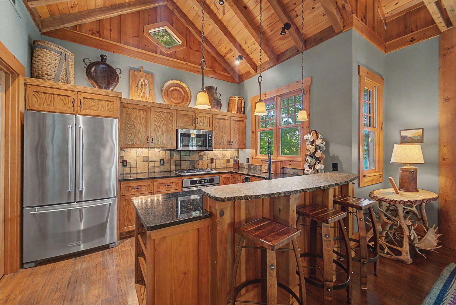 Kitchen with oak cabinetry, dark granite counters, stainless appliances, and a bar-height island
