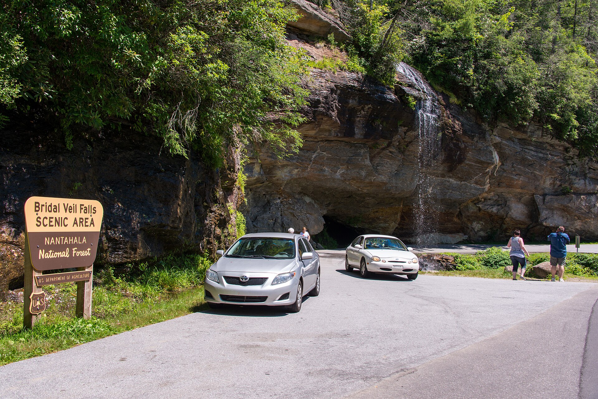 Bridal Veil Falls beside the highway, cars passing under the rock ledge