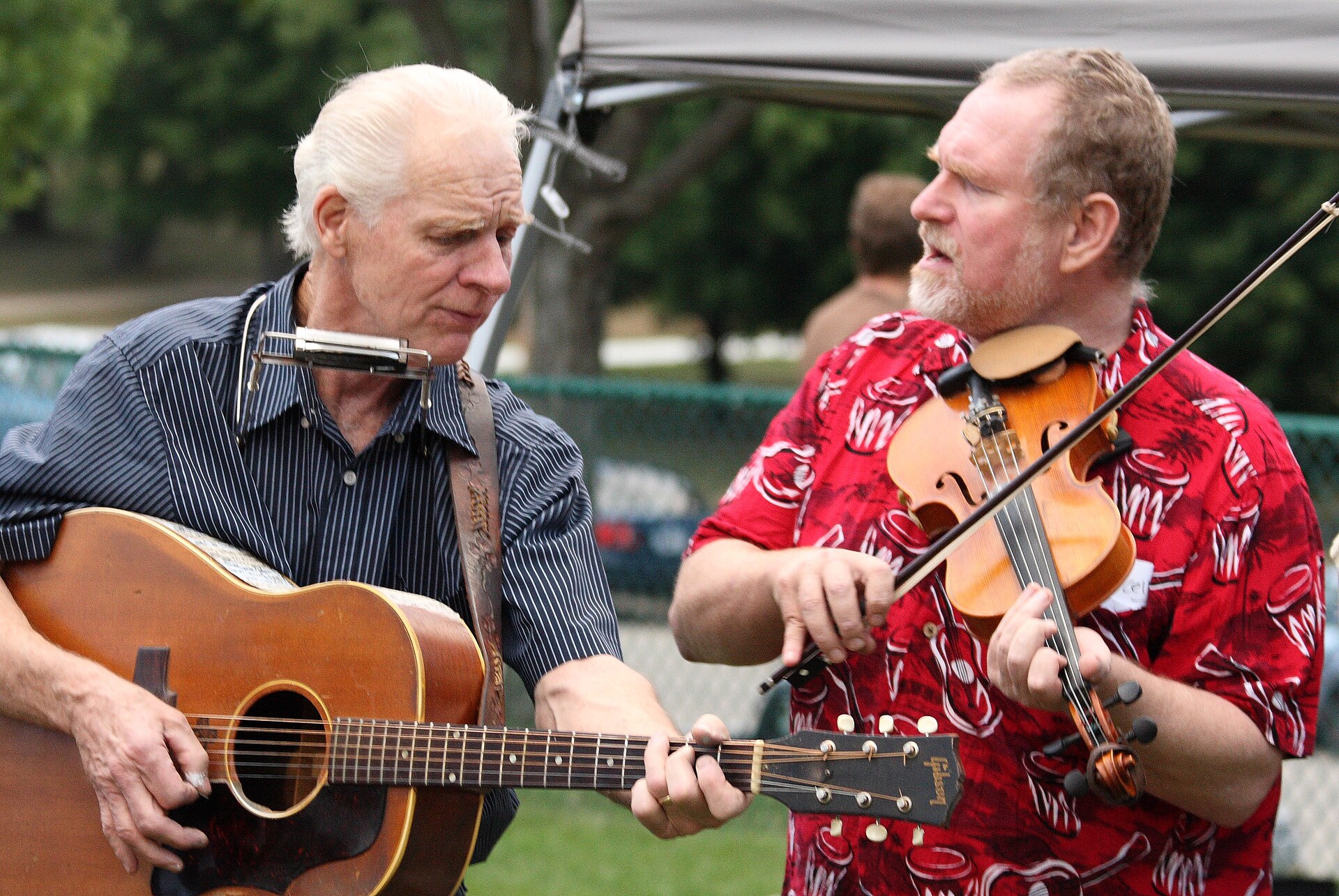 A guitarist and fiddler playing together outdoors